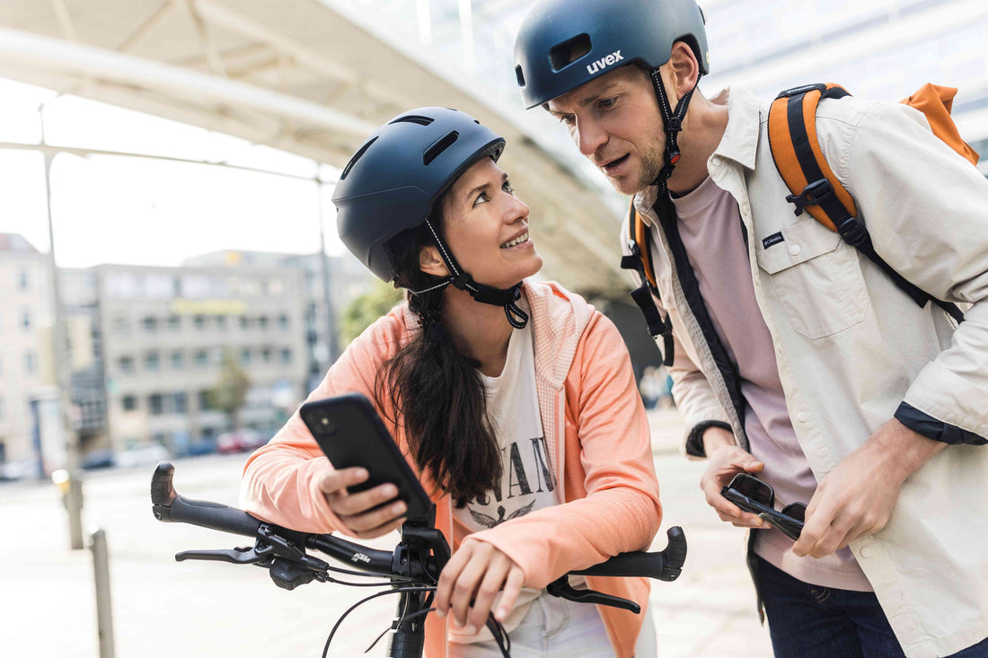 Pärchen, Frau und Mann, stehen am Bike und schauen ins Handy